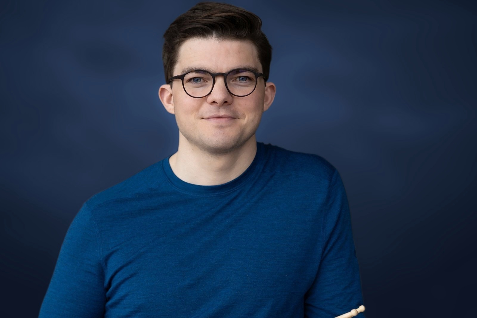Severin Stitzenberger in blauem Pullover vor einem farbigen Wandbild.