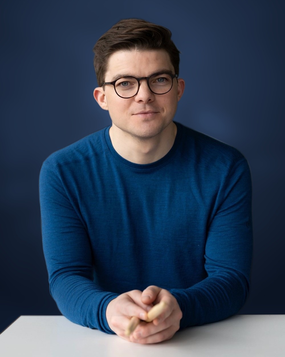 Severin Stitzenberger in blauem Pullover, die Hände mit Trommelstöcken auf einem Tisch.